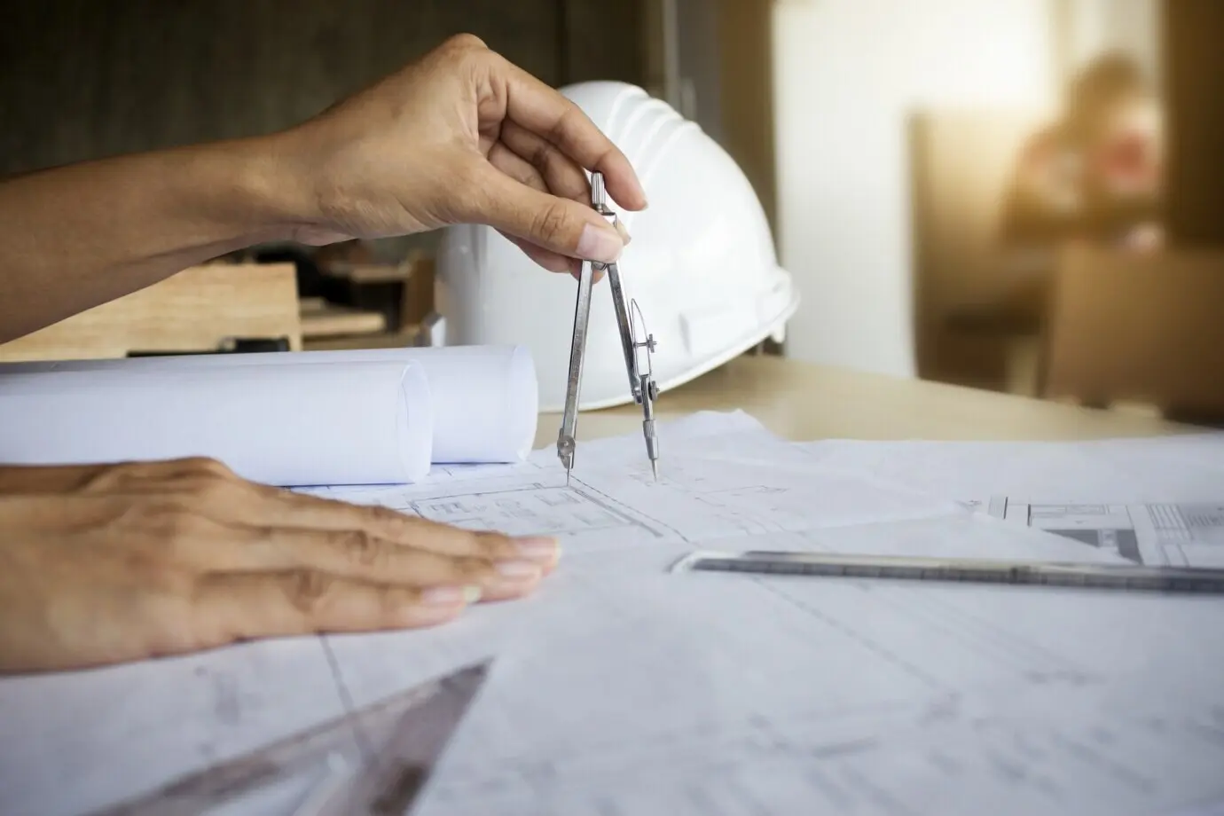 Hände eines Ingenieurs, der an einem Bauplan arbeitet; Baukonzept. Ingenieurwerkzeuge. Retro-Filtereffekt im Vintage-Ton, weicher Fokus (selektiver Fokus).